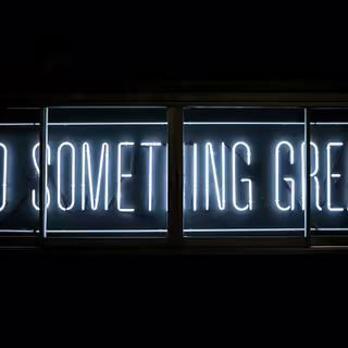 Text “Do Something great” in hellen Neo-Buchstaben auf schwarzer Wand.